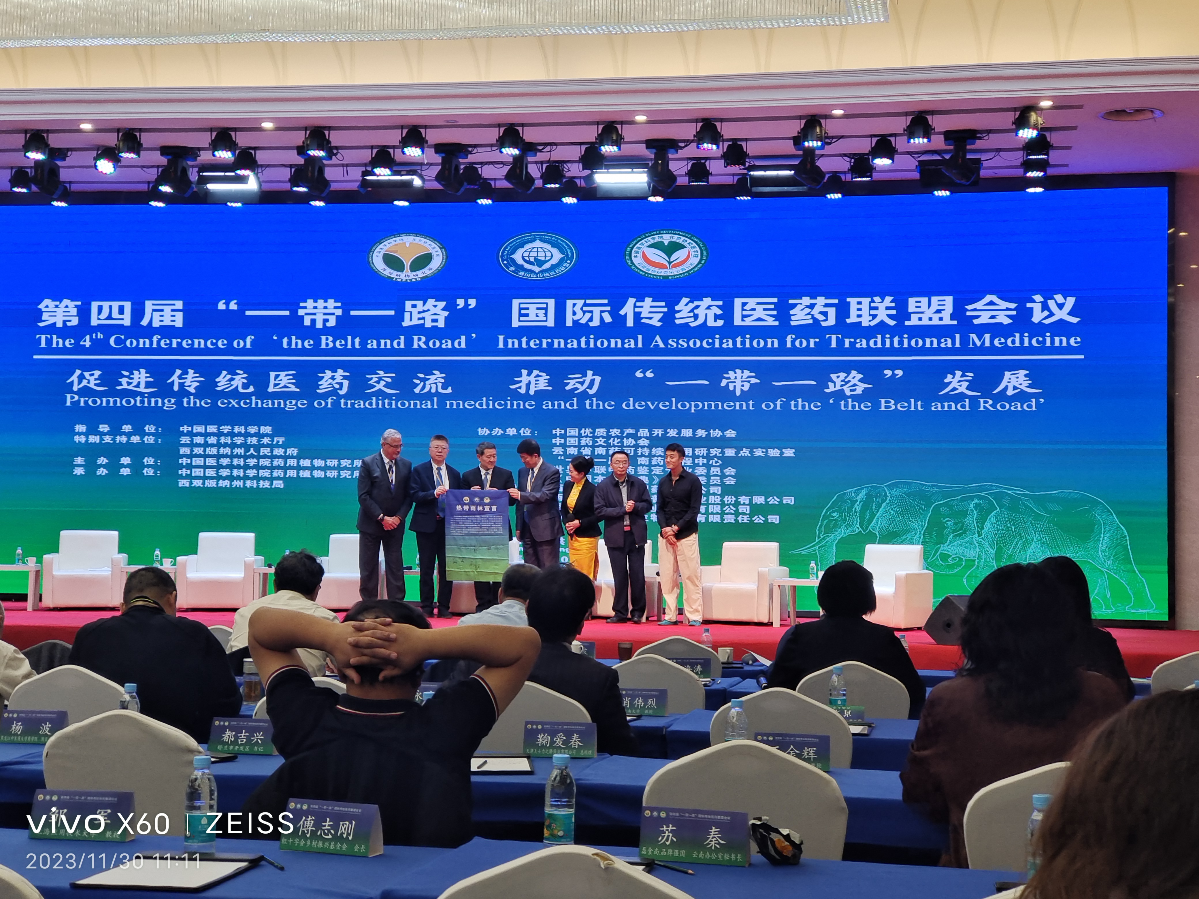 Delegates on stage holding a rainforest declaration scroll at the 4th Belt and Road International Association for Traditional Medicine conference