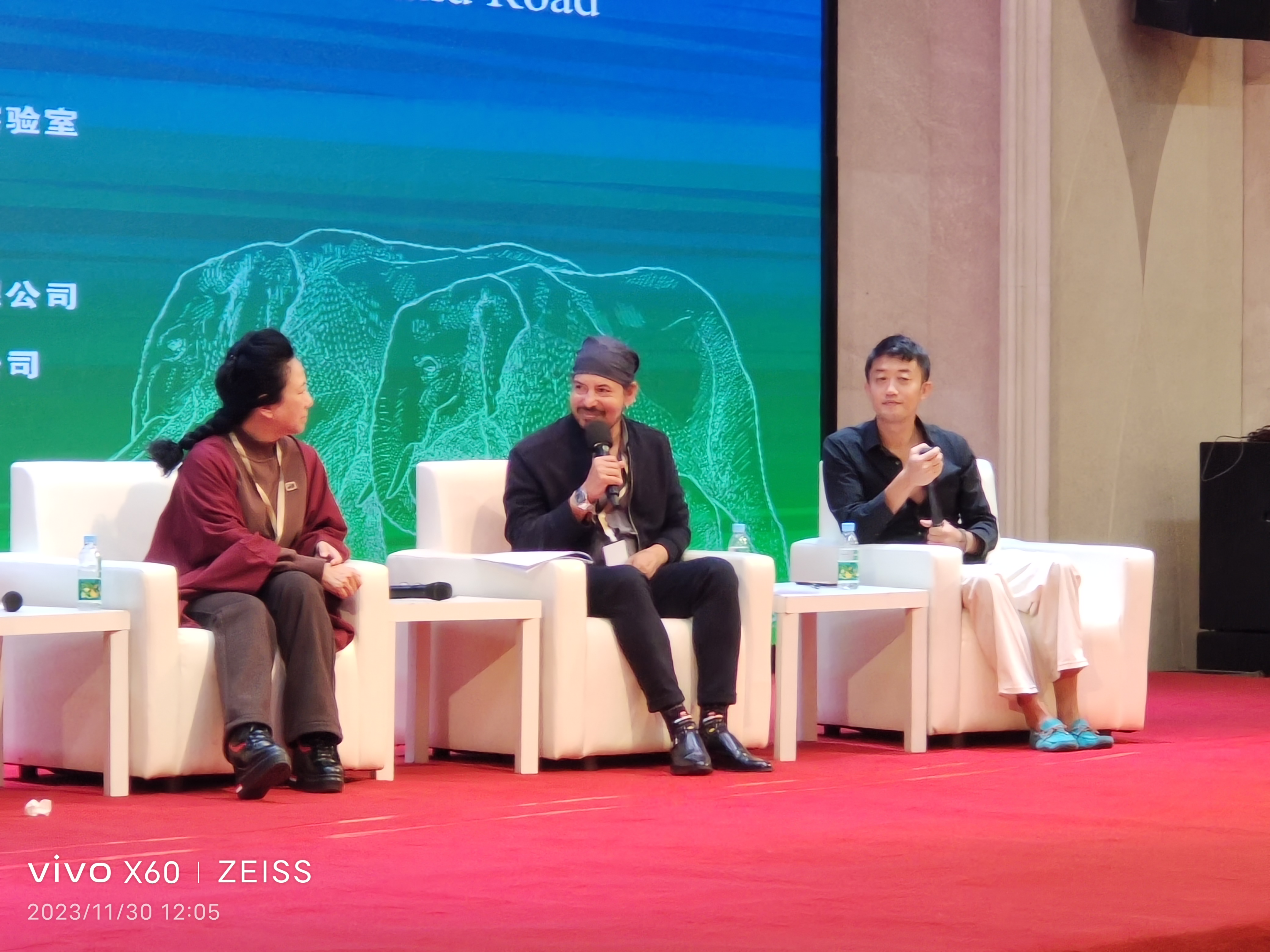 A three-person panel discussion on a red-carpeted stage during the traditional medicine conference