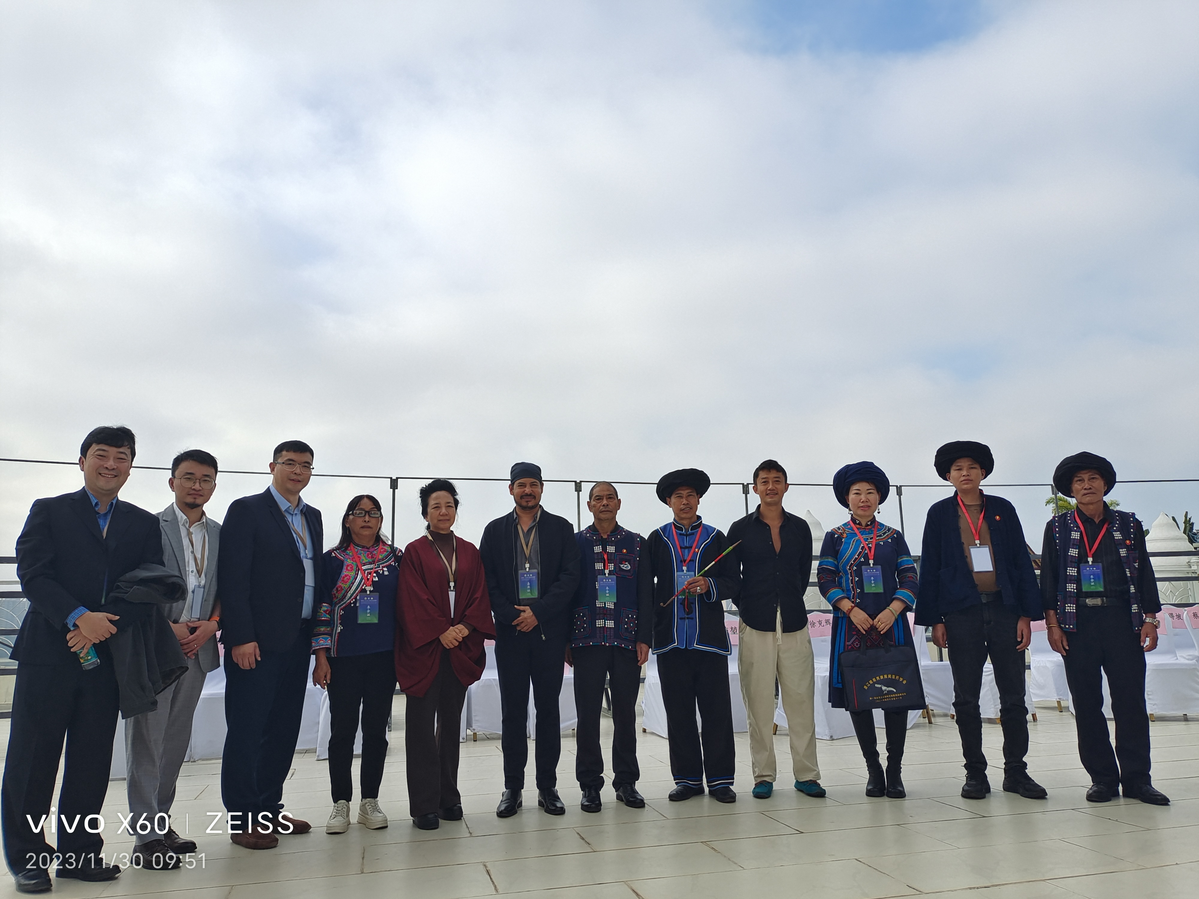 Farmsent representatives and Yunnan ethnic-minority community members in traditional dress posing together on a rooftop terrace